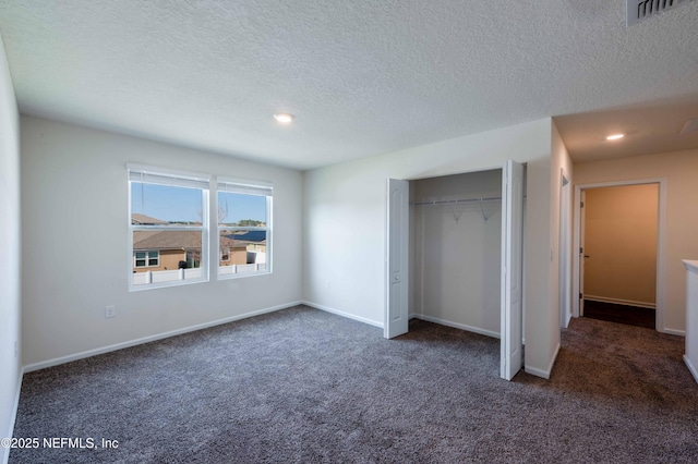 unfurnished bedroom with dark colored carpet, a textured ceiling, and a closet