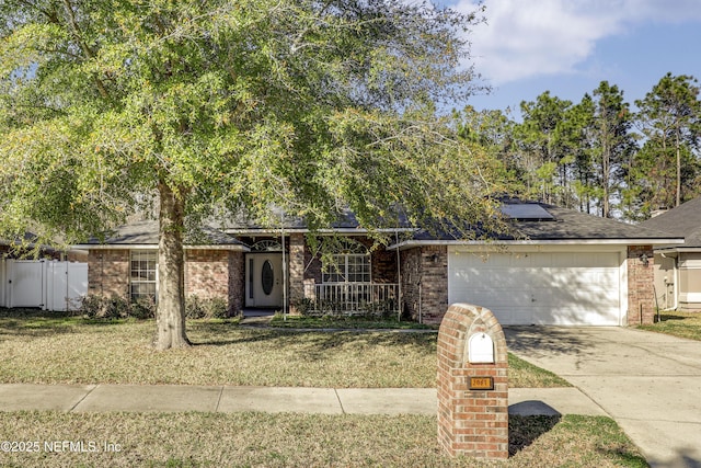 view of front of property featuring brick siding, roof mounted solar panels, a front yard, and a garage