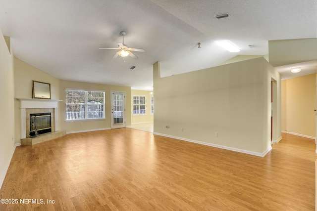 unfurnished living room with light wood-style flooring, a tiled fireplace, and vaulted ceiling