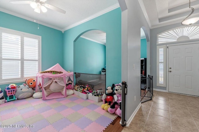 playroom with light tile patterned floors, a textured ceiling, ornamental molding, and ceiling fan