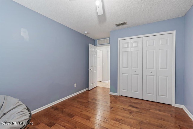 unfurnished bedroom featuring ceiling fan, dark hardwood / wood-style floors, a textured ceiling, and a closet