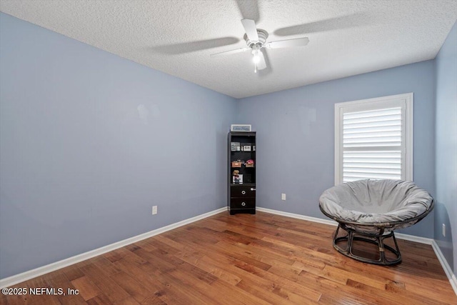 living area with ceiling fan, hardwood / wood-style floors, and a textured ceiling