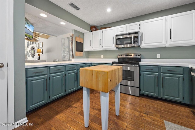 kitchen featuring white cabinetry, appliances with stainless steel finishes, dark wood-type flooring, and a textured ceiling