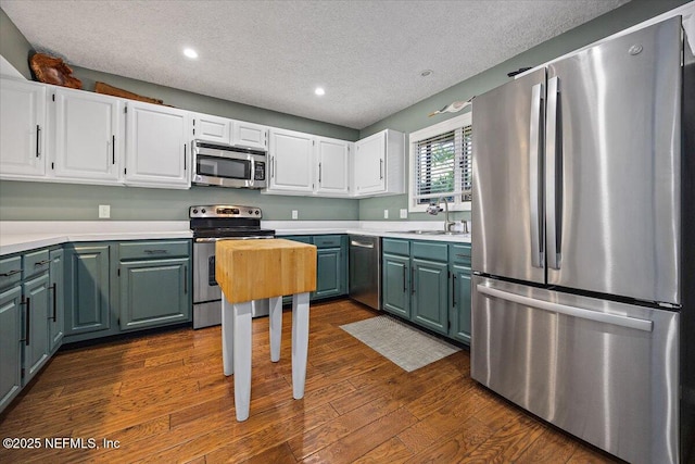 kitchen with sink, white cabinetry, a textured ceiling, dark hardwood / wood-style floors, and stainless steel appliances