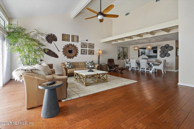 living room featuring ceiling fan, wood-type flooring, beam ceiling, and high vaulted ceiling