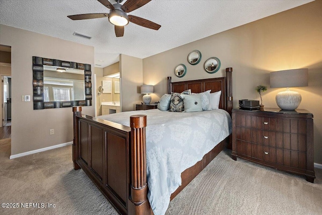 bedroom with ceiling fan, light colored carpet, ensuite bathroom, and a textured ceiling