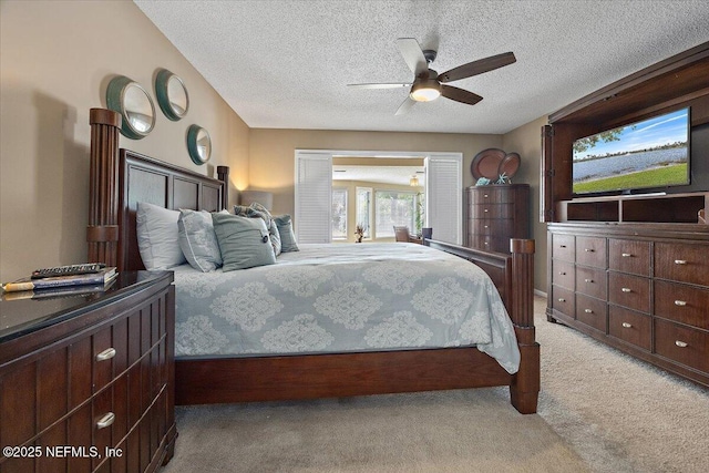 carpeted bedroom featuring ceiling fan and a textured ceiling