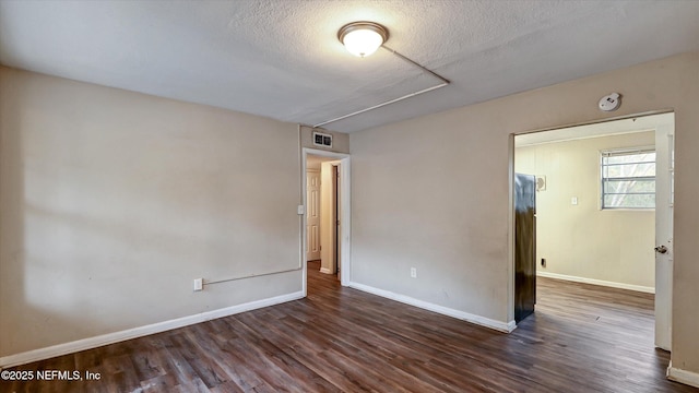 unfurnished room with dark hardwood / wood-style floors and a textured ceiling