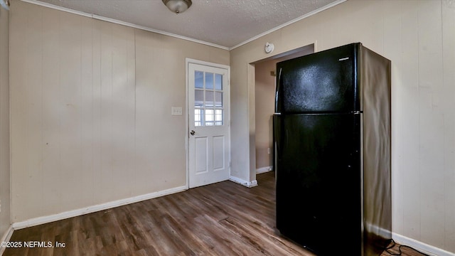 kitchen with black refrigerator, crown molding, a textured ceiling, and hardwood / wood-style flooring