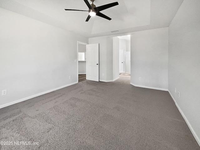 carpeted empty room with a tray ceiling and ceiling fan