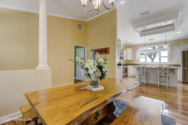94202 Christopher Ln, Fernandina Beach, FL 32034 - dining room with a raised ceiling, ornamental molding, decorative columns, and light wood-type flooring