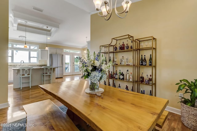 94202 Christopher Ln, Fernandina Beach, FL 32034 - dining space with ornamental molding, a tray ceiling, sink, and light hardwood / wood-style flooring