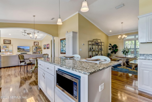94202 Christopher Ln, Fernandina Beach, FL 32034 - kitchen featuring white cabinetry, decorative light fixtures, light stone countertops, and a center island