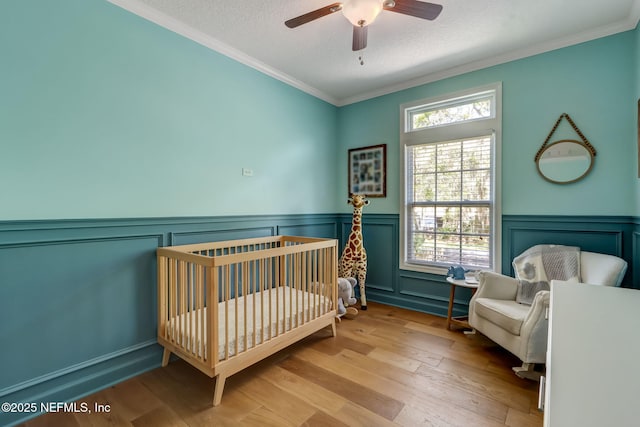 94202 Christopher Ln, Fernandina Beach, FL 32034 - bedroom featuring crown molding, a crib, a textured ceiling, and light wood-type flooring