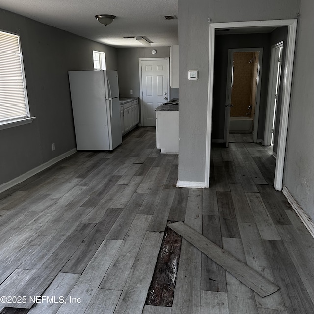 kitchen featuring white cabinetry, hardwood / wood-style floors, a textured ceiling, and white fridge