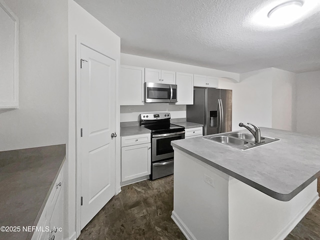 kitchen with sink, a textured ceiling, an island with sink, stainless steel appliances, and white cabinets