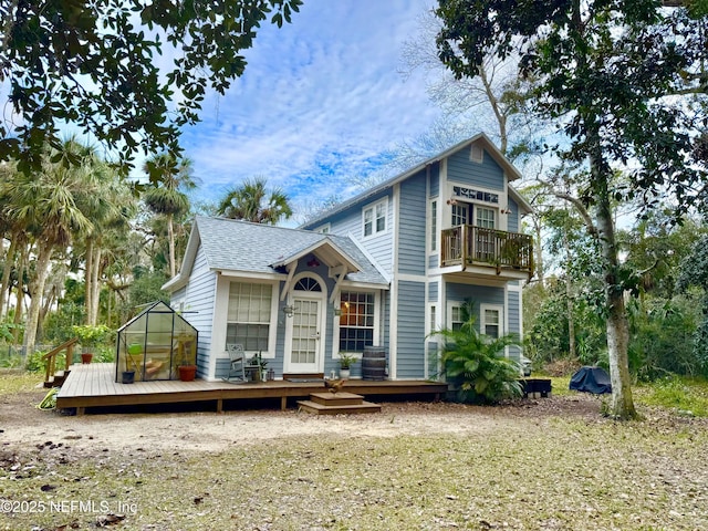 back of house featuring a balcony, a wooden deck, and roof with shingles