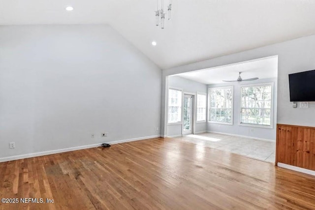 unfurnished living room with high vaulted ceiling, wood finished floors, a ceiling fan, and baseboards