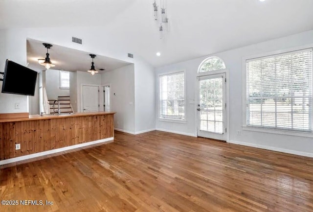 unfurnished living room with visible vents, stairway, vaulted ceiling, wood finished floors, and baseboards