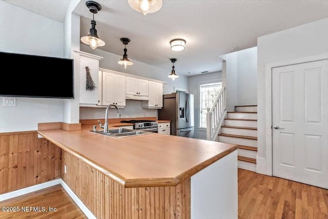 kitchen featuring a peninsula, light wood-style floors, appliances with stainless steel finishes, and a sink