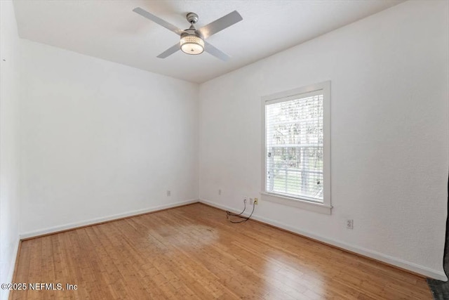 spare room featuring light wood finished floors, ceiling fan, and baseboards