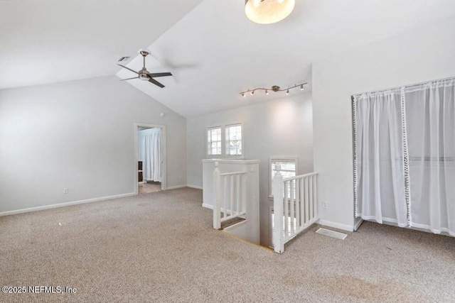 unfurnished room with lofted ceiling, carpet, a ceiling fan, and baseboards