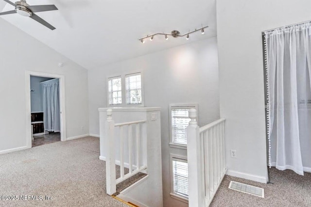 hallway with carpet floors, lofted ceiling, visible vents, an upstairs landing, and baseboards