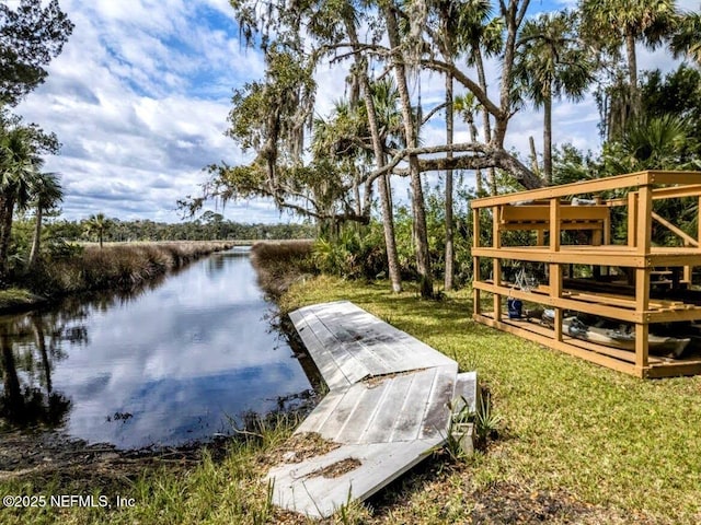 dock area with a yard and a deck with water view