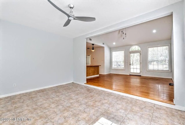 unfurnished living room featuring a ceiling fan, lofted ceiling, baseboards, and wood finished floors