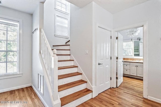 stairs featuring visible vents, baseboards, and wood finished floors