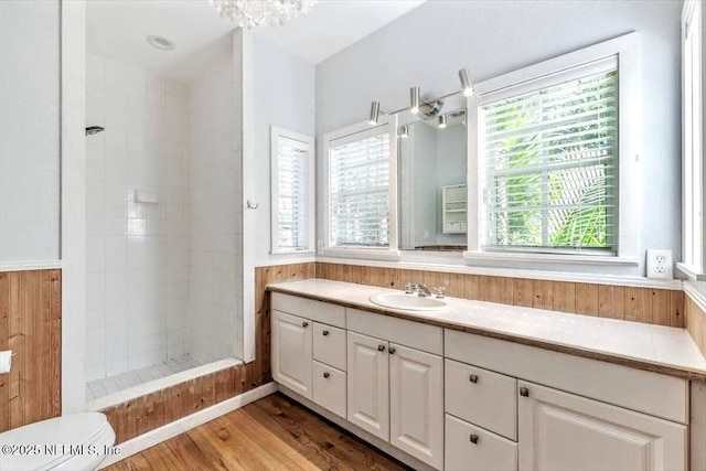 bathroom with wood finished floors, a tile shower, and vanity