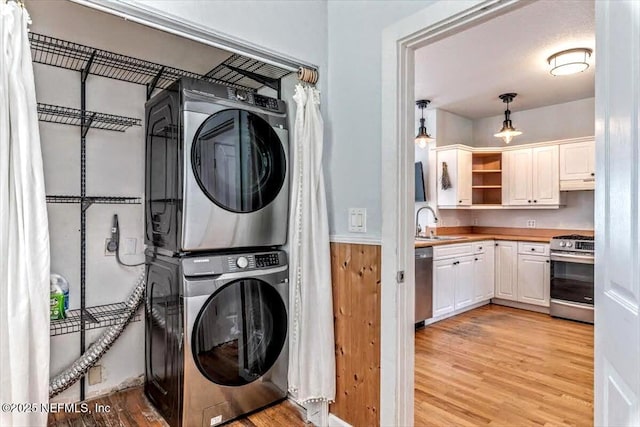 washroom with laundry area, a sink, light wood finished floors, and stacked washing maching and dryer