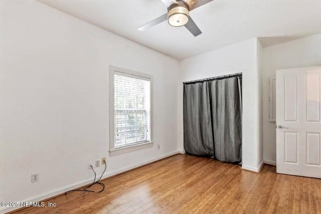 unfurnished bedroom with ceiling fan, light wood-style flooring, and baseboards