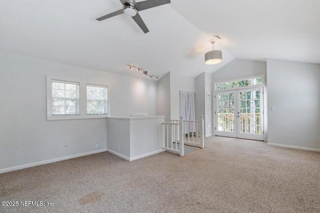 empty room featuring french doors, carpet flooring, vaulted ceiling, and baseboards