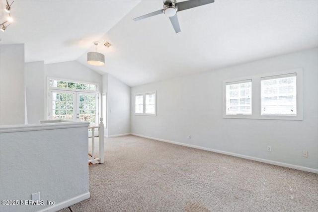 carpeted spare room featuring rail lighting, vaulted ceiling, visible vents, and baseboards