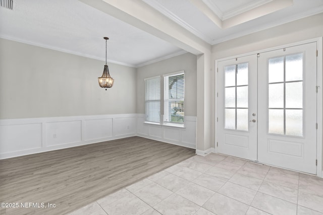 interior space with french doors, a notable chandelier, crown molding, and light wood-type flooring