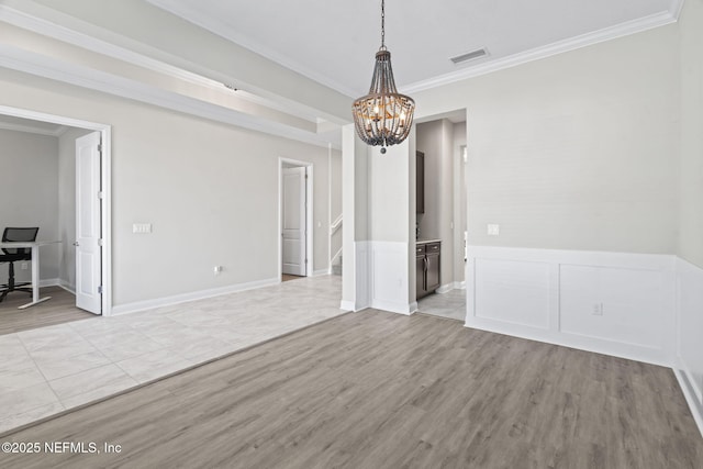 spare room featuring crown molding, light hardwood / wood-style floors, and a notable chandelier