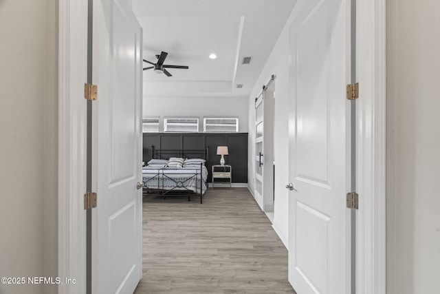 bedroom featuring ceiling fan, a barn door, and hardwood / wood-style floors