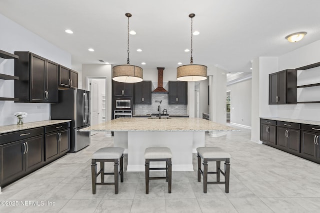 kitchen with premium range hood, a breakfast bar area, hanging light fixtures, a kitchen island with sink, and stainless steel appliances