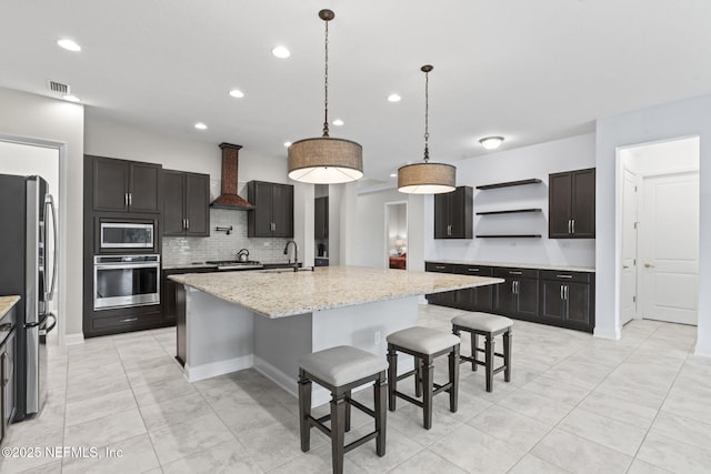 kitchen with custom exhaust hood, appliances with stainless steel finishes, a kitchen island with sink, and sink