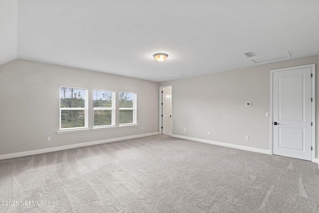 carpeted empty room featuring vaulted ceiling and a textured ceiling