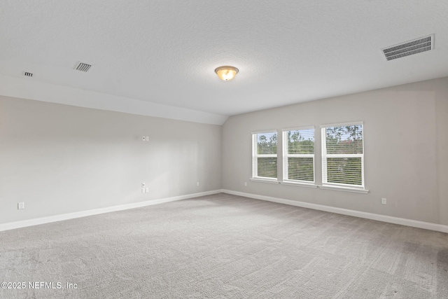 unfurnished room featuring carpet floors, a textured ceiling, and vaulted ceiling