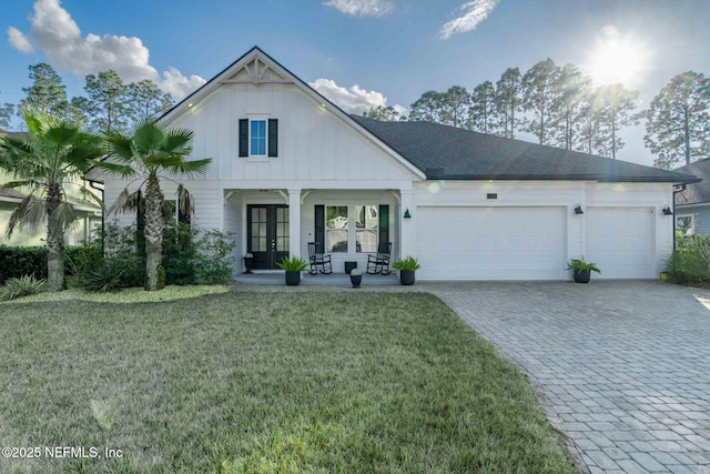 modern inspired farmhouse featuring french doors, a porch, a garage, and a front yard