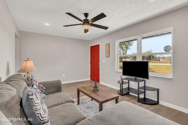 living room with ceiling fan, hardwood / wood-style flooring, and a textured ceiling