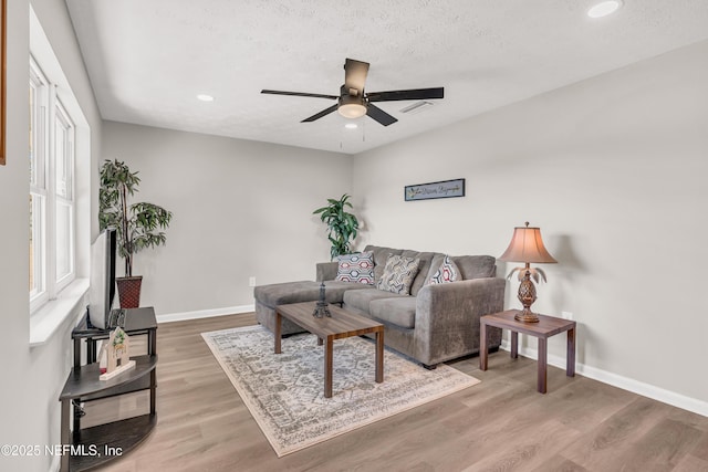 living room with ceiling fan, hardwood / wood-style flooring, and a textured ceiling