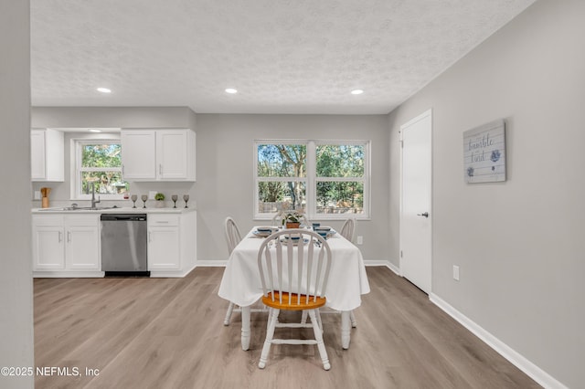 dining space featuring sink, a textured ceiling, and light hardwood / wood-style floors