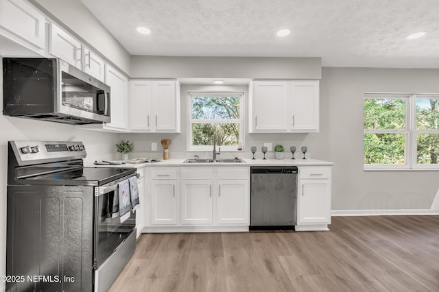 kitchen featuring stainless steel appliances, light hardwood / wood-style floors, sink, and white cabinets