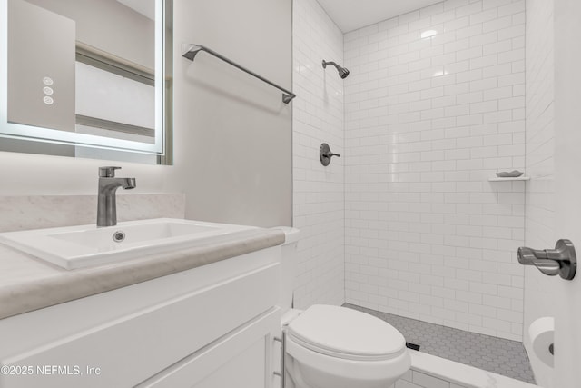 bathroom with tiled shower, vanity, and toilet