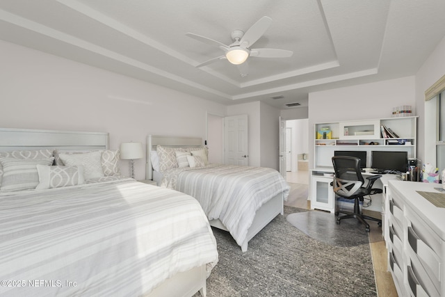 bedroom featuring hardwood / wood-style flooring, a raised ceiling, and ceiling fan