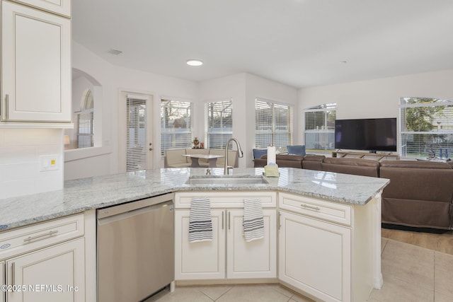 kitchen featuring sink, stainless steel dishwasher, light stone counters, and kitchen peninsula